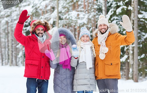 Image of group of friends waving hands in winter forest