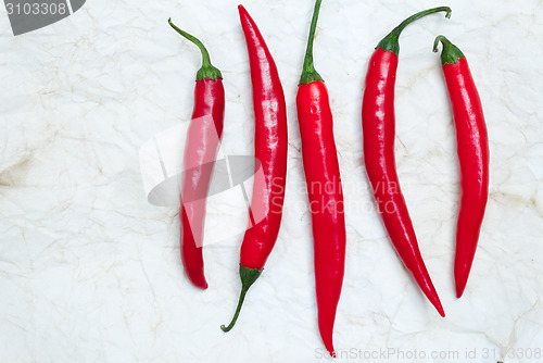 Image of five red hot chili peppers