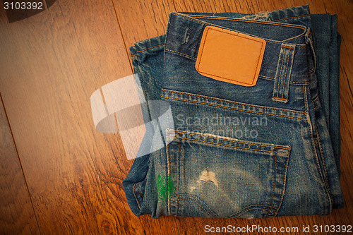 Image of old blue jeans with brown label on the belt smeared with green p