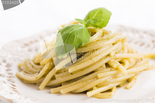Image of Italian pasta spaghetti with pesto sauce and basil leaf