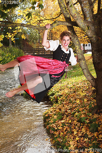 Image of Playful young woman swinging on a tree