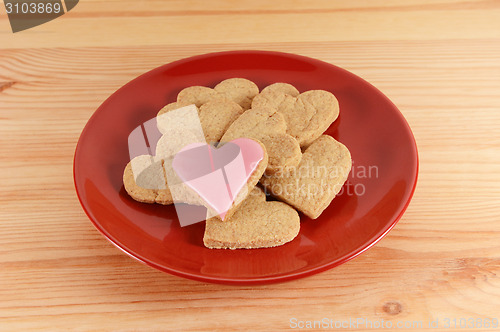Image of Iced and plain heart-shaped biscuits piled on a red plate 