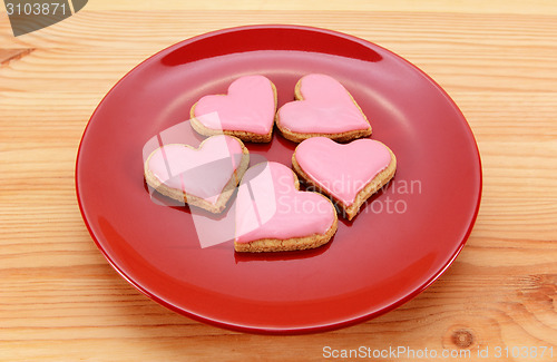 Image of Five heart-shaped iced cookies on a red plate 