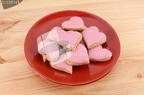 Image of Red plate stacked high with iced heart-shaped cookies