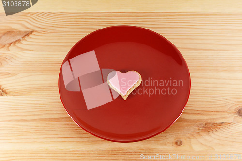 Image of Frosted heart-shaped cookie on a red plate 