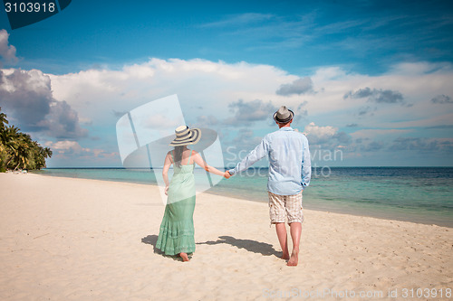 Image of Vacation Couple walking on tropical beach Maldives.