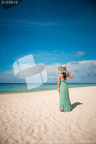 Image of Girl walking along a tropical beach in the Maldives.