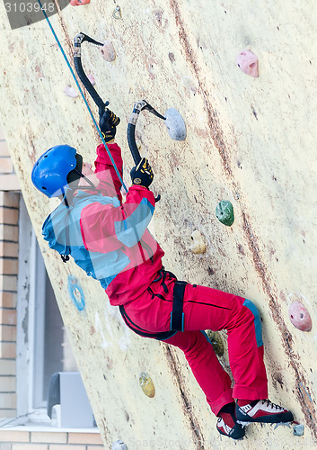 Image of Man climbs upward on ice climbing competition