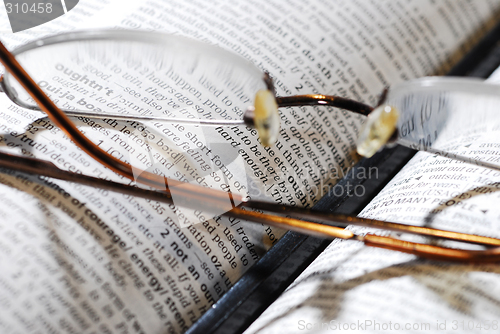 Image of eyeglasses, book and pencil