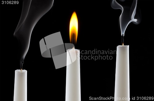 Image of burning candle with extinguished candles