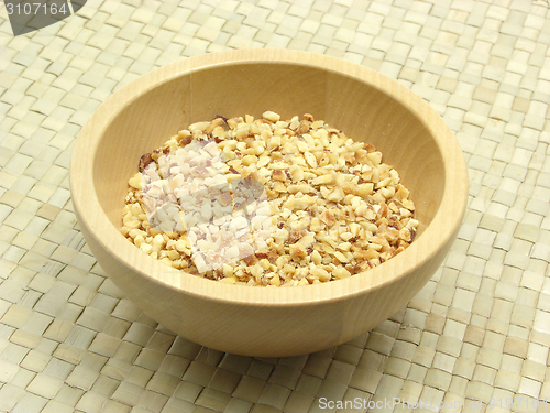 Image of Wooden bowl with roasted chopped hazelnuts on rattan underlay