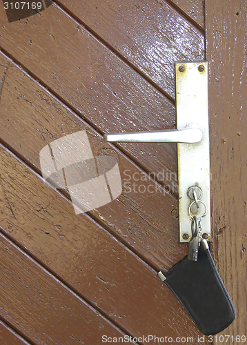 Image of The door latch of a wooden door with bunch of keys