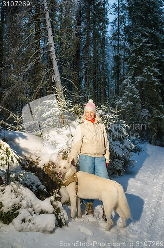 Image of Woman with dog in winter forest on a walk