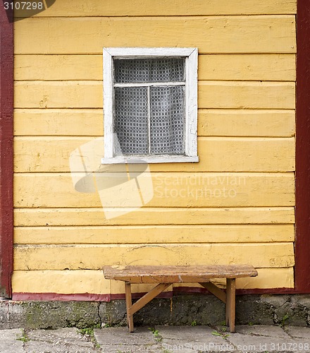 Image of bench near the wooden wall with window