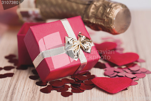Image of bottle of vine, red hearts and small present