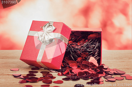 Image of Red hearts confetti on wooden background and bokeh