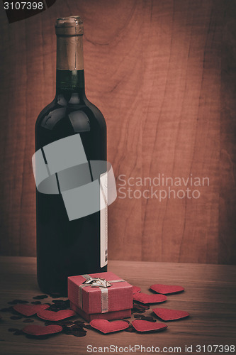 Image of bottle of vine, red hearts and small present a retro style