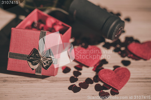 Image of bottle of vine, red hearts and small present a retro style