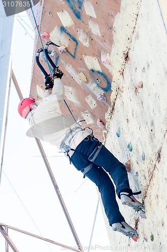 Image of Man climbs upward on ice climbing competition