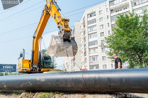 Image of Using of excavator as crane for raising of tube