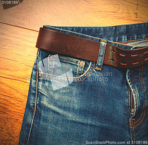 Image of Aged blue jeans with a leather belt 