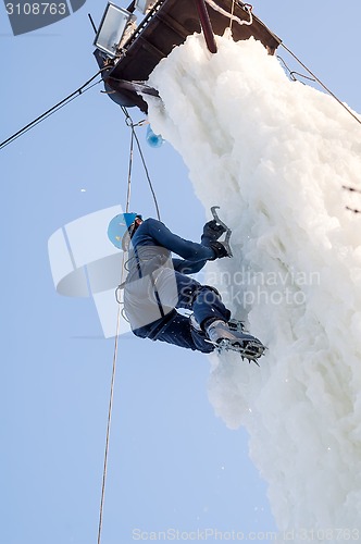 Image of Girl climbs upward on ice climbing competition