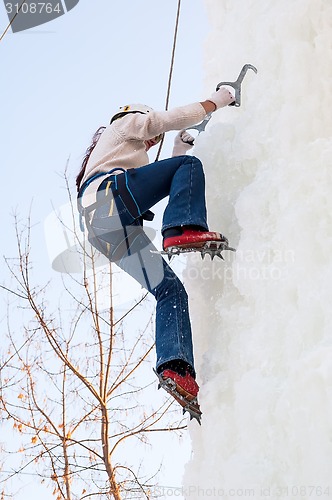 Image of Girl climbs upward on ice climbing competition