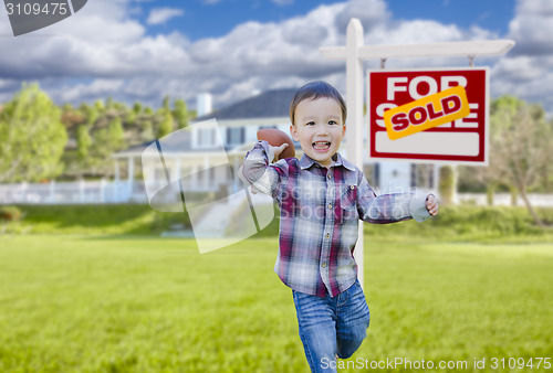 Image of Boy Playing Ball in Yard Near Sold Real Estate Sign