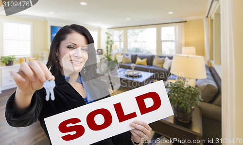 Image of Hispanic Woman with Keys and Sold Sign in Living Room