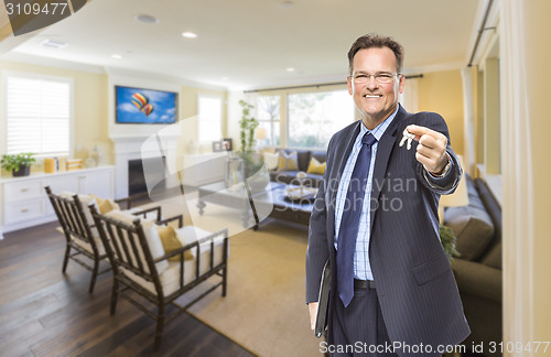 Image of Male Real Estate Agent Holding Keys in Beautiful Living Room