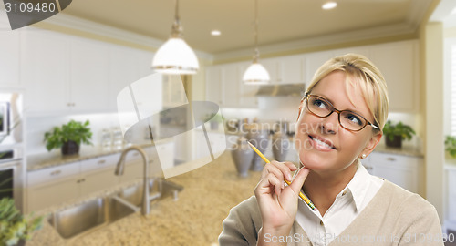 Image of Daydreaming Woman with Pencil Inside Beautiful Kitchen