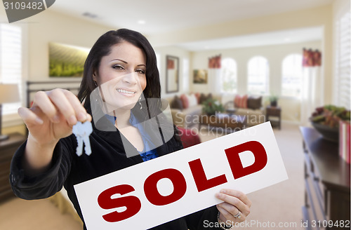 Image of Hispanic Woman with Keys and Sold Sign in Living Room