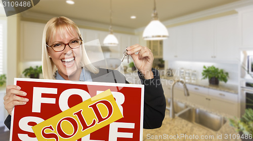 Image of Young Woman Holding Blank Sign and Keys Inside Kitchen