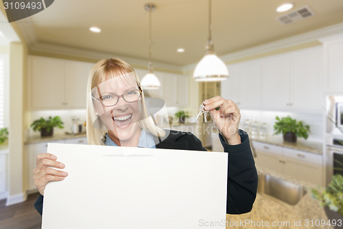 Image of Young Woman Holding Blank Sign and Keys Inside Kitchen