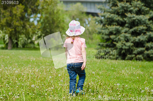 Image of Girl walking on the grass with dandelions