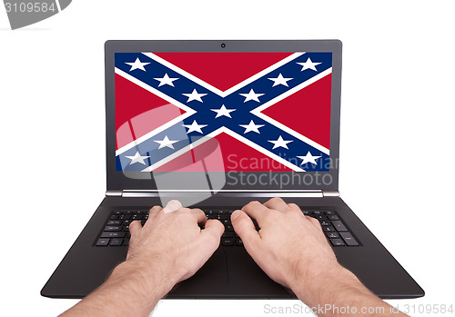 Image of Man working on laptop, confederate flag