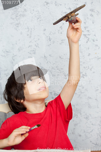 Image of boy in a red shirt with a wooden plane