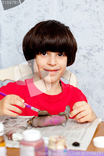 Image of boy paints a wooden plane