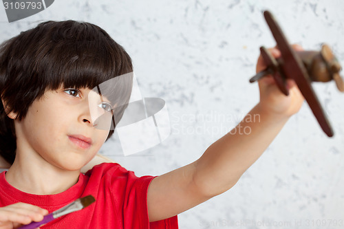 Image of portrait of a boy with a wooden plane and brush