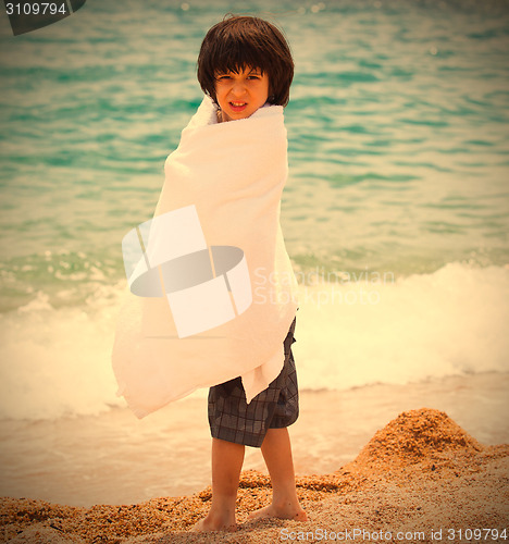 Image of boy wrapped in a white towel on the beach