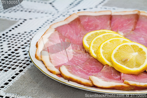 Image of The dish with slices of ham and lemon 