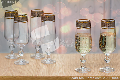 Image of Six beautiful glass wine glasses, two filled with champagne.