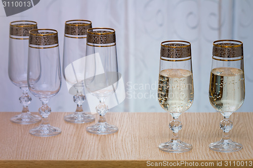 Image of Six beautiful glass wine glasses, two filled with champagne.
