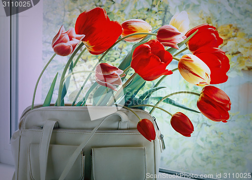 Image of Flowers tulips and a women bag on a window window sill.