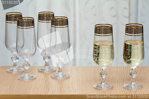 Image of Six beautiful glass wine glasses, two filled with champagne.