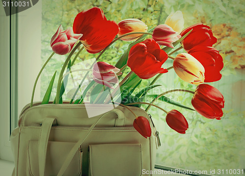 Image of Flowers tulips and a women bag on a window window sill.