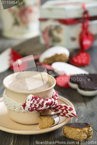 Image of  Cup of cocoa and gingerbread heart on wooden table.