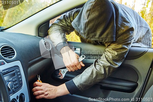 Image of Hooligan breaking into car