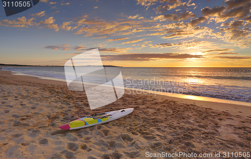 Image of Beach sunrise and paddleboard on shoreline