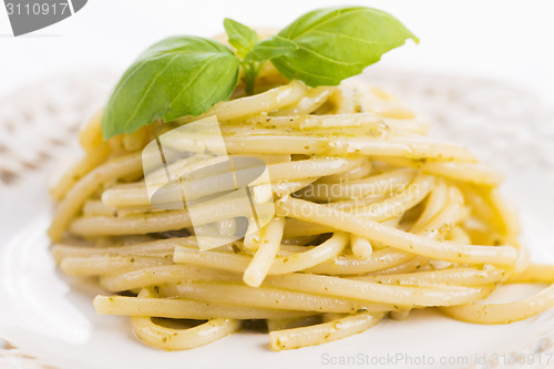 Image of Italian pasta spaghetti with pesto sauce and basil leaf